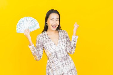 Asyalı güzel bir kadının portresi. Renkli arka planda bol para ve parayla gülümsüyor.