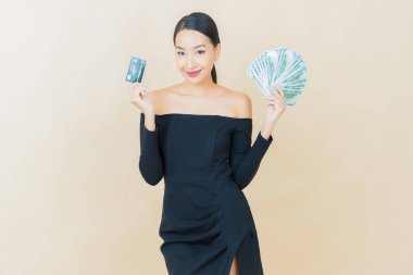 Asyalı güzel bir kadının portresi. Renkli arka planda bol para ve parayla gülümsüyor.