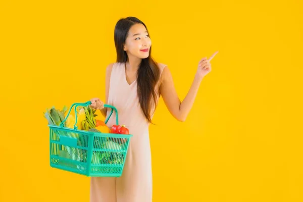 ポートレート美しい若いですアジアの女性で食料品バスケットショッピングバッグスーパーマーケットからクレジットカードで黄色隔離された背景 — ストック写真
