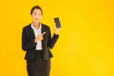 Portre güzel genç Asyalı kadın akıllı cep telefonu ve kahve fincanı ile izole edilmiş sarı arka planda