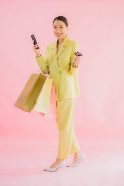Renkli arka planda alışveriş çantası taşıyan güzel Asyalı iş kadını portresi.