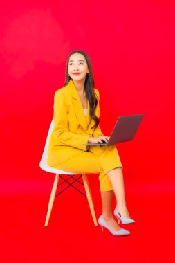 Portre güzel genç iş kadını Asyalı kadın kırmızı arka planda bilgisayar bilgisayarı kullanıyor