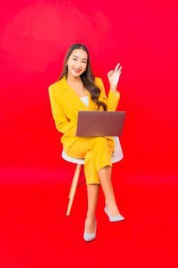 Portre güzel genç iş kadını Asyalı kadın kırmızı arka planda bilgisayar bilgisayarı kullanıyor