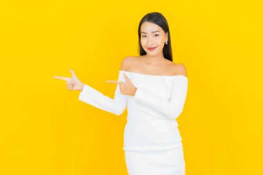 Portre güzel genç iş kadını gülümseyen ve eylem sarı arka planlı Asyalı kadın