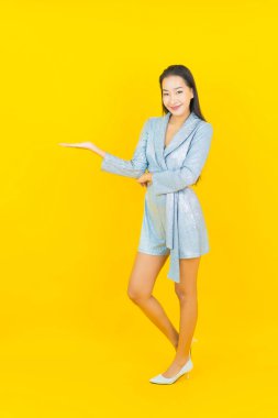 Asyalı güzel bir kadının portresi. Sarı arka planda hareketli gülümsüyor.