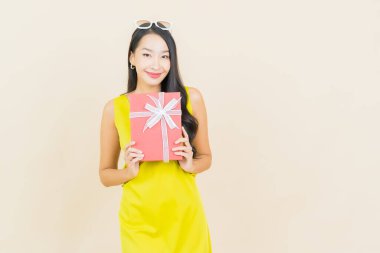 Güzel bir Asyalı kadının portresi. Arka planda kırmızı hediye kutusuyla gülümsüyor.