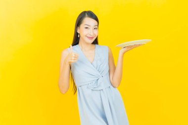 Güzel Asyalı bir kadının portresi. Arka planda boş tabak tabağıyla gülümsüyor.