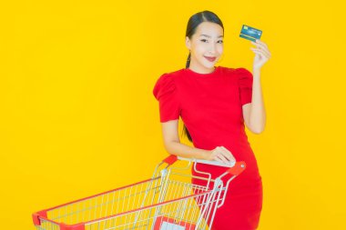 Renkli arka planda süpermarketten alınmış market sepetiyle gülümseyen güzel Asyalı kadın portresi.