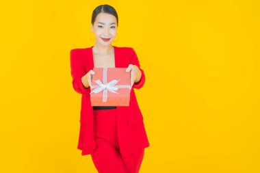 Güzel bir Asyalı kadının portresi. Arka planda kırmızı hediye kutusuyla gülümsüyor.