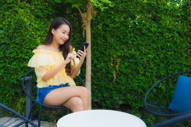 Genç Asyalı kadın açık hava manzarası için akıllı cep telefonu kullanıyor.