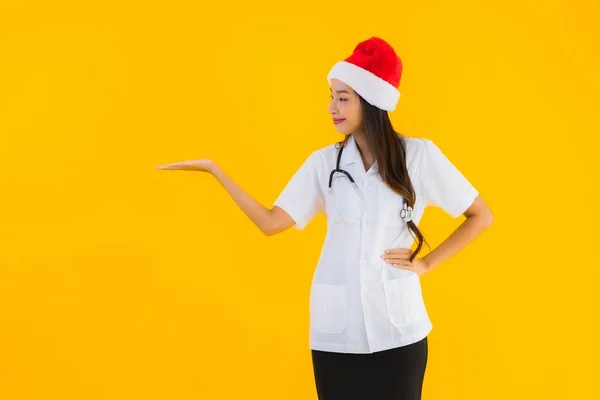 亚洲年轻貌美的女医生 戴着圣诞或圣诞礼帽 背景是黄色的 孤立的 — 图库照片