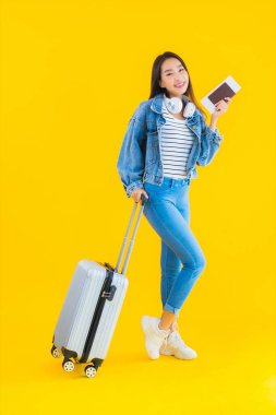 Güzel, Asyalı genç bir kadının portresi valiz ve pasaport ile seyahat, sarı izole arka planda biniş kartı.