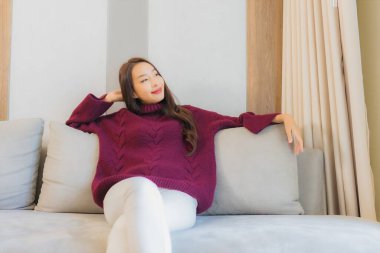 Portre güzel Asyalı kadın gülümsemesi. Oturma odasındaki kanepede rahatla.