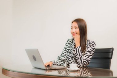 Güzel bir Asyalı kadın çalışma masasında bilgisayar kullanıyor.