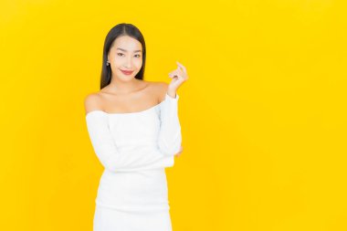 Portre güzel genç iş kadını gülümseyen ve eylem sarı arka planlı Asyalı kadın