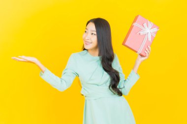 Güzel bir Asyalı kadının portresi. Arka planda kırmızı hediye kutusuyla gülümsüyor.