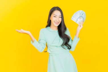 Asyalı güzel bir kadının portresi. Renkli arka planda bol para ve parayla gülümsüyor.