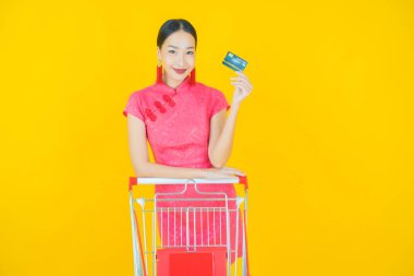 Renkli arka planda süpermarketten alınmış market sepetiyle gülümseyen güzel Asyalı kadın portresi.