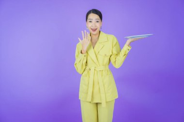 Güzel Asyalı bir kadının portresi. Arka planda boş tabak tabağıyla gülümsüyor.