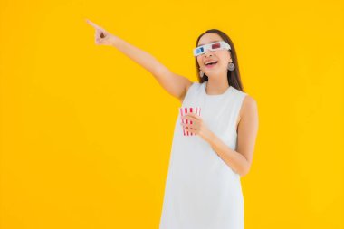 Sarı izole edilmiş arka planda patlamış mısır ve 3 boyutlu gözlüklü güzel Asyalı kadın portresi.