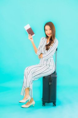 Güzel Asyalı bir kadının portresi. Bavul pasaportu ve biniş kartı mavi arka planda seyahat için hazır.