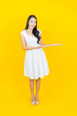 Asyalı güzel bir kadının portresi. Sarı arka planda hareketli gülümsüyor.