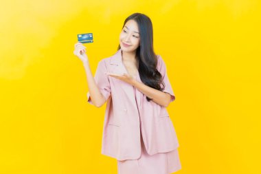 Güzel bir Asyalı kadının portresi. Renkli kredi kartıyla gülüyor.