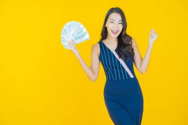 Asyalı güzel bir kadının portresi. Renkli arka planda bol para ve parayla gülümsüyor.