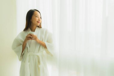 Yatak odasının içinde kahve fincanı olan güzel Asyalı genç kadınların portresi.