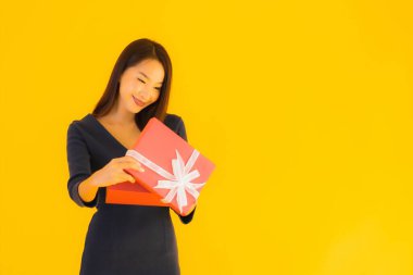 Sarı izole edilmiş arka planda hediye kutusu olan güzel Asyalı kadın portresi.