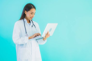 Bilgisayarlı güzel Asyalı doktor kadın portresi klinikte ya da mavi izole arka planda hastanede kullanılacak.