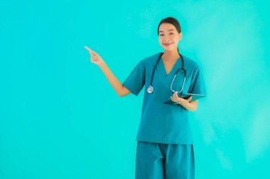Güzel Asyalı genç doktor kadın mavi izole arka planda akıllı tablet aygıtı kullanıyor.