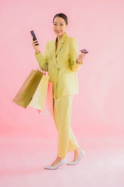 Renkli arka planda alışveriş çantası taşıyan güzel Asyalı iş kadını portresi.