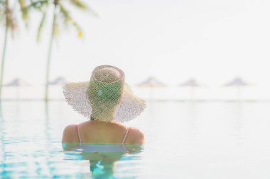 Güzel bir Asyalı kadın portresi. Tatil gezisinde deniz manzaralı açık havuz etrafında rahatça yüzebiliyor.