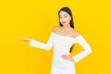 Portre güzel genç iş kadını gülümseyen ve eylem sarı arka planlı Asyalı kadın