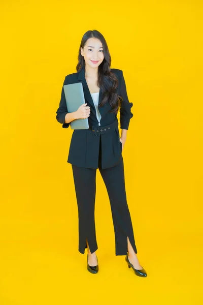外型美丽的年轻亚洲女人带着电脑笔记本电脑在与世隔绝的背景下微笑 — 图库照片