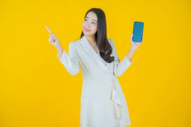 Renkli arka planda akıllı cep telefonuyla güzel Asyalı kadın gülümsemesi