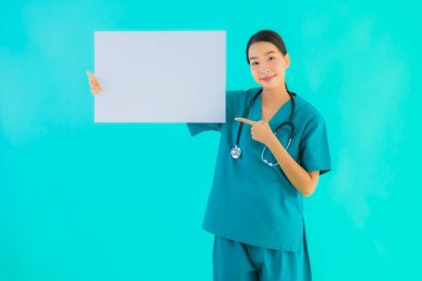 Fotokopi için boş kâğıt tahtası olan güzel Asyalı genç doktor kadın hastane ve klinikteki sağlık hizmetleri konseptinde mavi izole edilmiş arka plan.