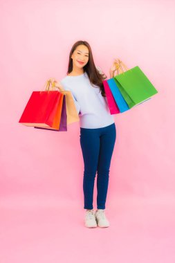 Portrait beautiful young asian woman with colorful shopping bag on pink color isolated background