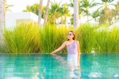 Güzel bir Asyalı kadın portresi. Rahatlayın, gülümseyin. Tatil için oteldeki yüzme havuzunun keyfini çıkarın.