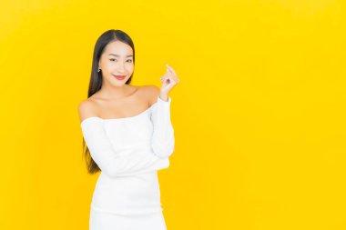 Portre güzel genç iş kadını gülümseyen ve eylem sarı arka planlı Asyalı kadın