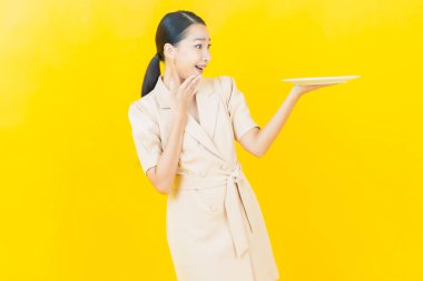 Güzel Asyalı bir kadının portresi. Arka planda boş tabak tabağıyla gülümsüyor.