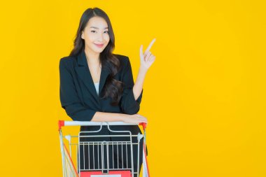 Renkli arka planda süpermarketten alınmış market sepetiyle gülümseyen güzel Asyalı kadın portresi.