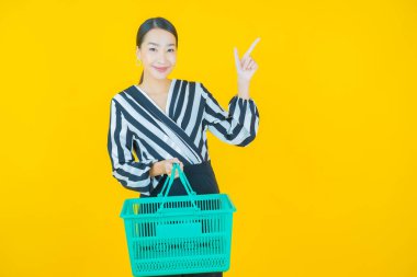 Renkli arka planda süpermarketten alınmış market sepetiyle gülümseyen güzel Asyalı kadın portresi.