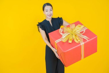 Güzel bir Asyalı kadının portresi. Arka planda kırmızı hediye kutusuyla gülümsüyor.