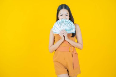 Asyalı güzel bir kadının portresi. Renkli arka planda bol para ve parayla gülümsüyor.