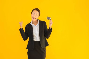 Sarı izole edilmiş arka planda kredi kartı olan güzel, genç Asyalı kadın portresi.