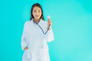 Klinikte ya da mavi izole edilmiş arka planda hastanede kullanmak üzere steteskoplu güzel Asyalı genç doktor kadın portresi.
