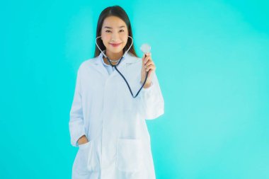 Klinikte ya da mavi izole edilmiş arka planda hastanede kullanmak üzere steteskoplu güzel Asyalı genç doktor kadın portresi.