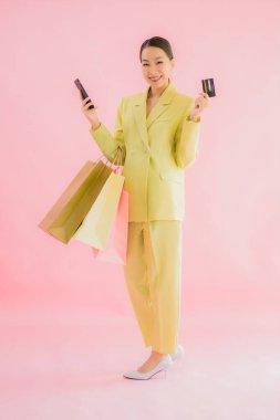 Renkli arka planda alışveriş çantası taşıyan güzel Asyalı iş kadını portresi.